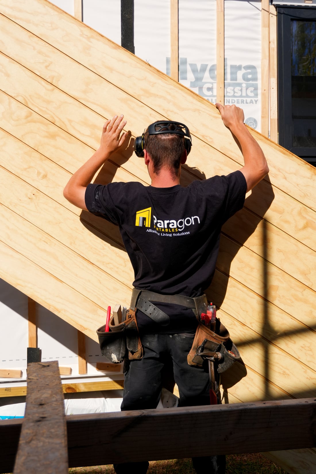 A Paragon Portables builder fitting cladding over the building wrap