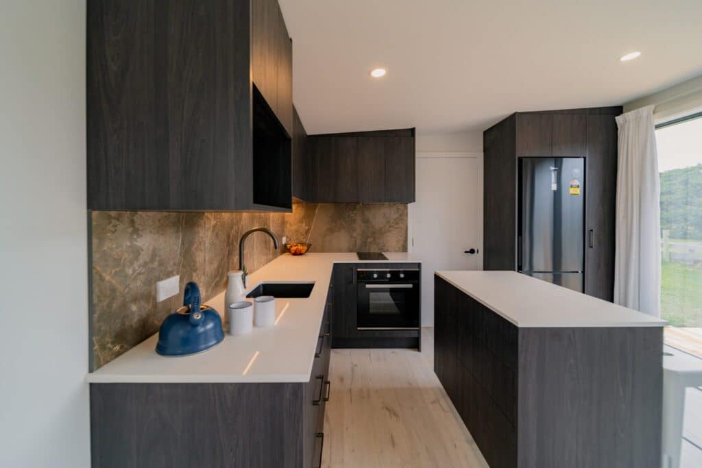 Charcoal kitchen with island and stone splashback in a Paragon Portables home