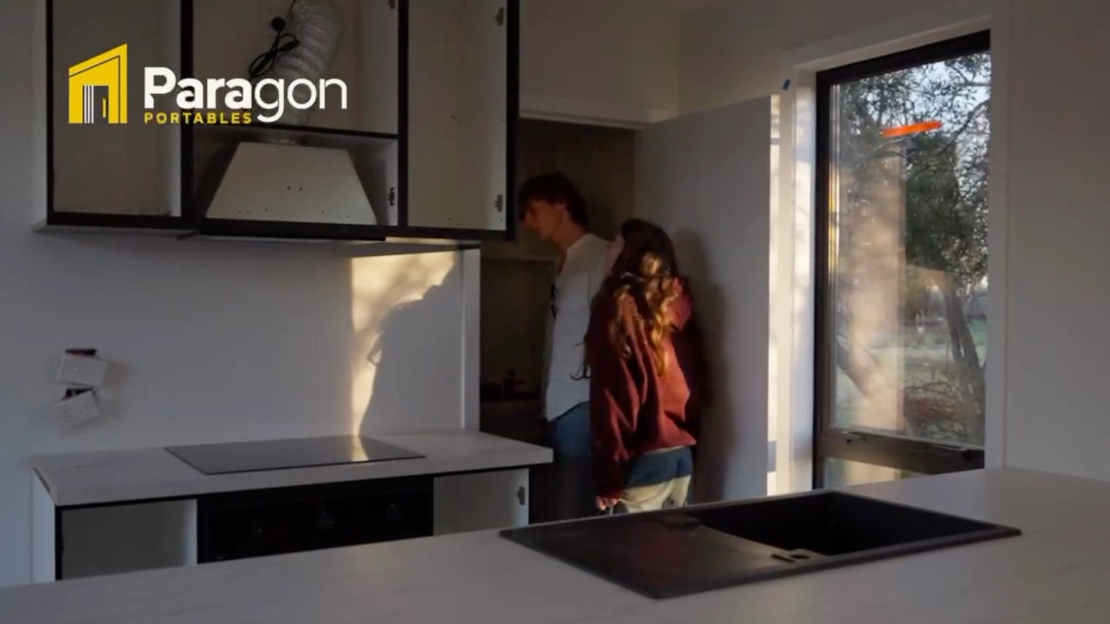 A couple looking through the kitchen and living space of a finished Paragon Portables home